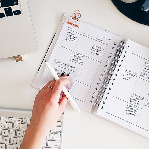 Person's hand on a their planner/calendar.